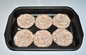 Фарш стал эластичным, из него мы легко лепим шарики, которые разминаем в некрупные лепешки, кладем их в промазанную маслом форму. И пальцами или стаканом проминаем углубление, оставляя по кругу бортик.